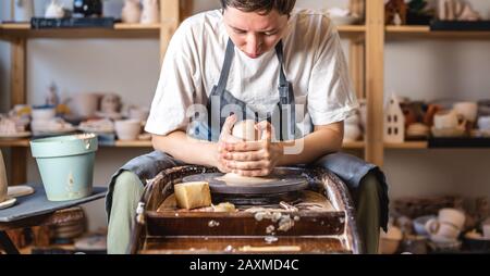 Potter che lavora su una ruota di Potter che fa un vaso. Giovane donna che forma l'argilla con le mani creando brocca in un laboratorio Foto Stock