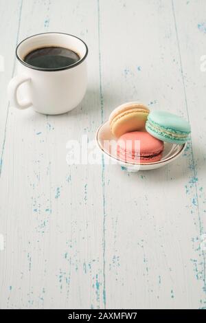 colorati macaroni francesi e una tazza di caffè su un tavolo di legno Foto Stock