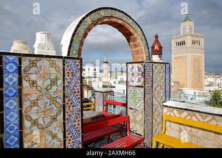 Colorata terrazza piastrellata affacciata sulla medina di Tunisi, Tunisia, con vista sul minareto della Moschea Ez Zitouna (Grande Moschea) e sul minareto di Cam Foto Stock