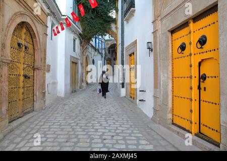 Tipica strada acciottolata e stretta (via Dar el Jeld) con porte colorate, colonne e portici all'interno della storica medina di Tunisi, Tunisia Foto Stock