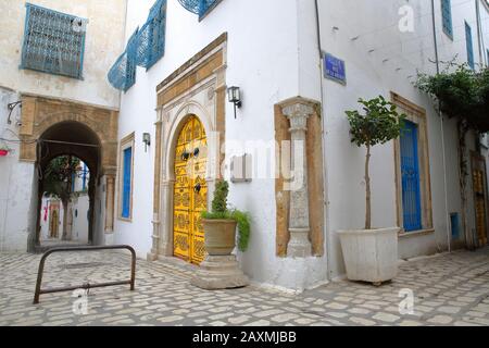 Tipiche strade acciottolate e strette con porte colorate, colonne e portici all'interno della storica medina di Tunisi, Tunisia Foto Stock