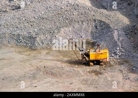 macchina per carver giallo, escavatore, scalpellatore per granito industriale in una cava vicino a pietre di granito Foto Stock