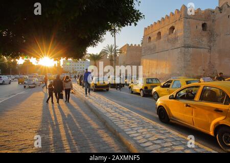 Sfax, TUNISIA - 22 DICEMBRE 2019: Gli imponenti bastioni della medina con un taxi al tramonto (stella del sole) Foto Stock