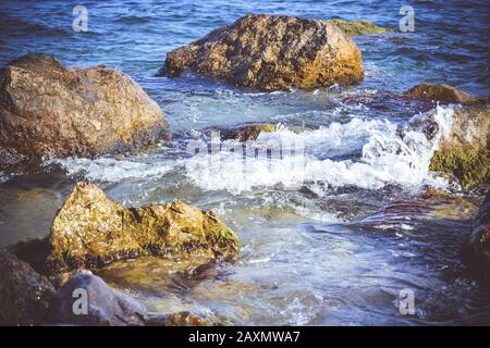 gruppo di pietre in acqua con schiuma bianca Foto Stock