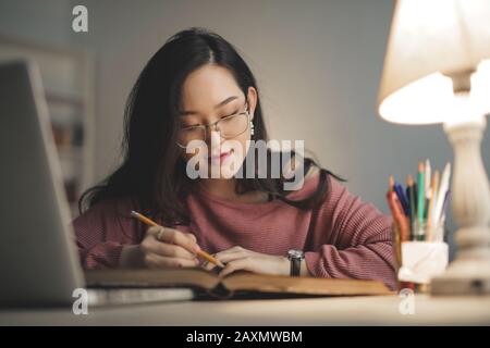 giovane donna asiatica che studia a casa Foto Stock