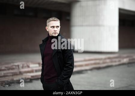 Uomo serio in trenchcoat nero e collo polo viola Foto Stock