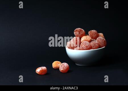 una ciotola di kumquat rivestita di zucchero isolato su sfondo nero. L'immagine contiene spazio di copia Foto Stock