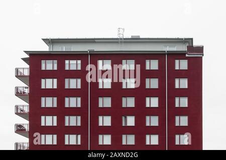 Moderno edificio rosso ciliegia contro il cielo nuvoloso. Stoccolma, Svezia. Foto Stock