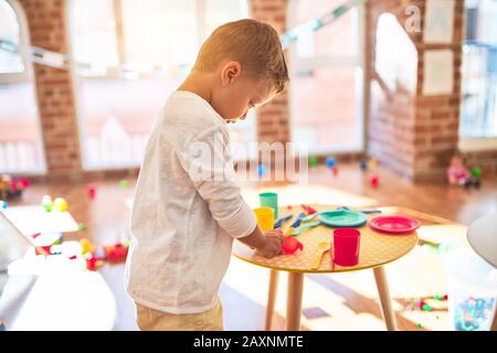 Bella bionda toddler giocando in plastica con cibi e piatti. Piedi intorno un sacco di giocattoli a kindergarten Foto Stock