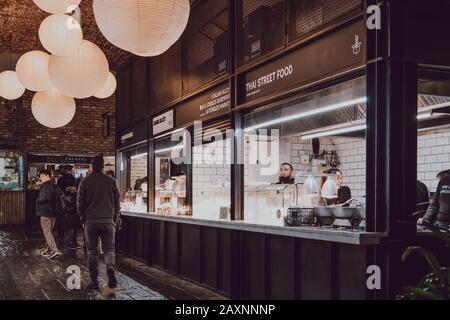 Londra, Regno Unito - 26 novembre 2019: Fila di bancarelle alimentari all'interno di Camden Market, Londra, persone a piedi. Iniziato con 16 bancarelle nel 1974, Camden Market è uno Foto Stock