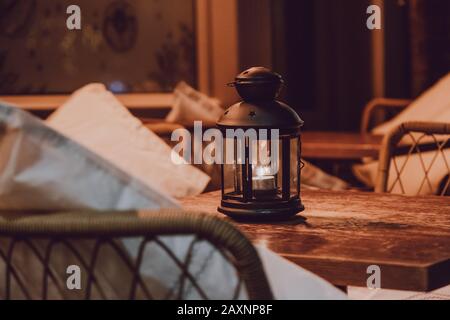 Primo piano di una lampada a candela su un tavolo esterno di notte, atmosfera accogliente, fuoco selettivo. Foto Stock