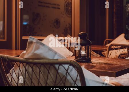 Primo piano di una lampada a candela su un tavolo esterno di notte, atmosfera accogliente, fuoco selettivo. Foto Stock