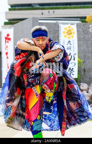 Primo piano di ballerini maschi danzanti con naruko, clappers, all'aperto al festival Kyusyu Gassai, Kumamoto. Costume tradizionale molto colorato. Rivolto Verso L'Alto. Foto Stock