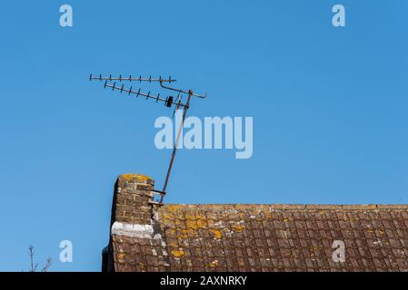 Un'antenna TV della casa danneggiata da Storm Ciara, appesa ad angolo su un camino. Antenna tv montata esternamente sul tetto della casa Foto Stock