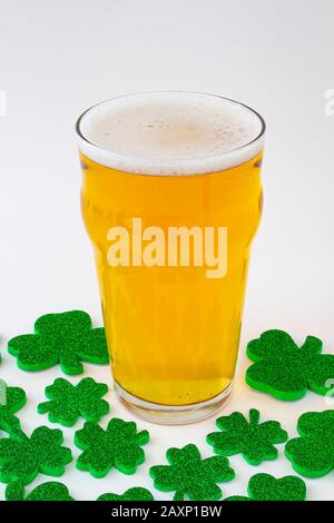 Una Pinta di birra con i verdi trifogli intorno Foto Stock