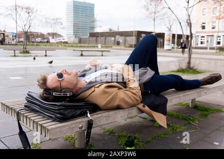 L’uomo d’affari ha una pausa su una panchina del parco Foto Stock