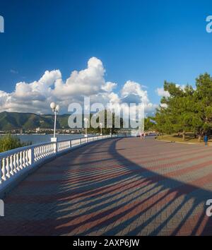 Gelendzhik passato in una chiara giornata di sole. A sinistra è la balaustra e il mare. Lunghe ombre dalla balaustra cadono sulle piastrelle del pavimento. In t Foto Stock