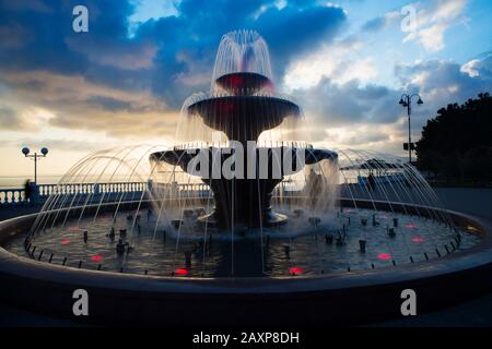 Fontana di canto sul Lermontov Boulevard nella città di Gelendzhik resort al tramonto. Le luci del terrapieno, la balaustra e l'acqua del Foto Stock