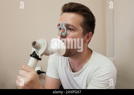 Giovane uomo che prova la funzione di respirazione dalla spirometria che ha problemi di salute. Foto Stock