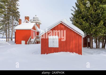 Edifici rossi con persiane bianche incastonato nella neve profonda e incorniciato da pini verdi. Foto Stock