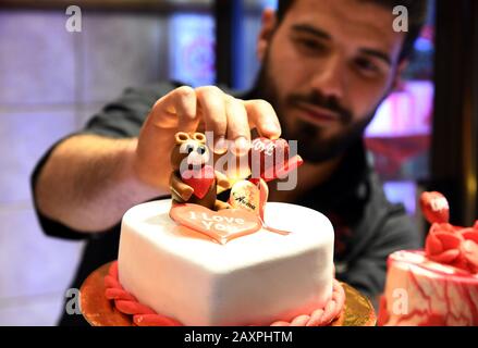 Damasco, Siria. 12th Feb, 2020. Un dolce produttore mette i tocchi finali su una torta a forma di cuore in occasione del giorno di San Valentino a Damasco, in Siria, il 12 febbraio 2020. Credit: Ammar Safarjalani/Xinhua/Alamy Live News Foto Stock
