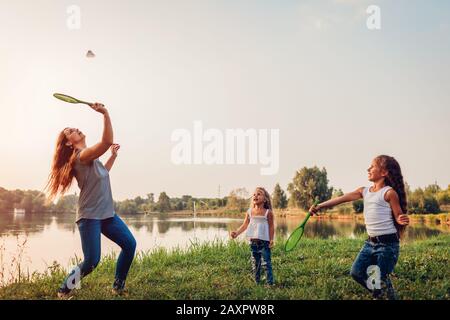 Giorno della madre. Donna che gioca a badminton e divertirsi con le figlie nel parco estivo. Tempo di famiglia Foto Stock