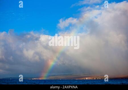 Arcobaleno che si inarcano su edifici su una costa. Foto Stock