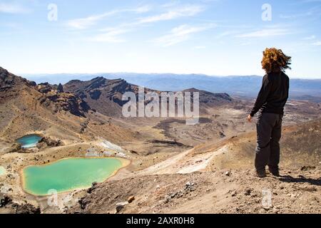 Escursionista maschile con capelli ricci, guardando la vista dei laghi smeraldo Foto Stock