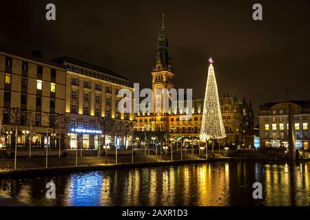 Vista notturna del lago Binnenalster e del mercato di Natale nella piazza del Municipio vicino al Municipio di Amburgo (Hamburg Rathaus), Germania Foto Stock