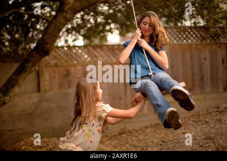 Ragazza adolescente spingendo amico su corda swing. Foto Stock