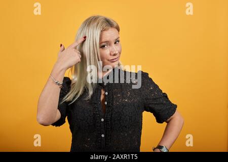 ragazza in abito nero donna elegante tocca il suo tempio con indice dito Foto Stock