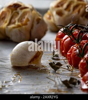 Bulbi d'aglio arrosto e pomodori ciliegini. Foto Stock