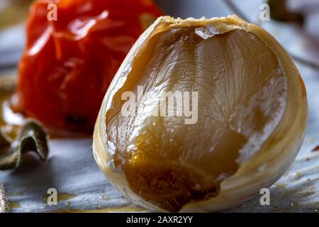 Bulbi d'aglio arrosto e pomodori ciliegini. Foto Stock