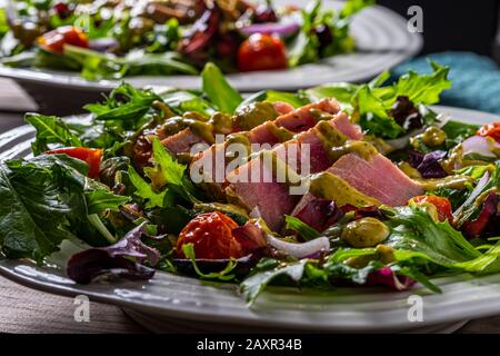 Bistecca di tonno affettato alla griglia sulla cima di verdure di insalata. Foto Stock