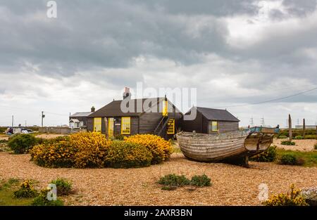 Vista laterale di Prospect Cottage, casa di Derek Jarman, regista, sulla spiaggia di ghiaia a Dungeness, quartiere Shepway, Kent con vecchia barca Foto Stock