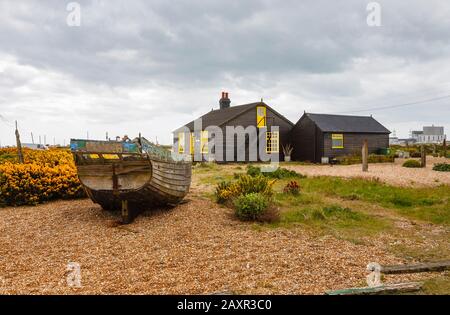 Vista laterale di Prospect Cottage, casa di Derek Jarman, regista, sulla spiaggia di ghiaia a Dungeness, quartiere Shepway, Kent con vecchia barca Foto Stock