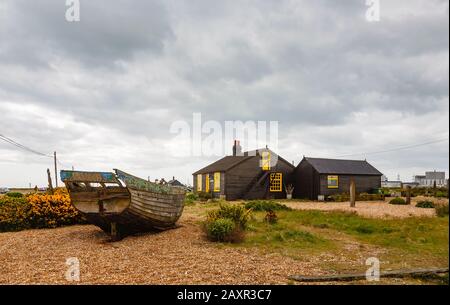 Vista laterale di Prospect Cottage, casa di Derek Jarman, regista, sulla spiaggia di ghiaia a Dungeness, quartiere Shepway, Kent con vecchia barca Foto Stock