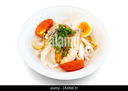 Pesce noodle tailandese mescolato tra gamberi bolliti, calamari, maiale, uova e verdure colorate in ciotola bianca. Foto Stock