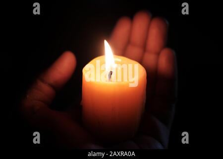 candela bruciante sulla mano delle donne di notte, primo piano Foto Stock