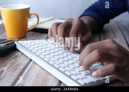 Primo piano della mano d'uomo con la tastiera sul tavolo Foto Stock