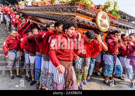 Santiago Atitlan, Guatemala - 19 aprile 2019: Gli uomini maya in costume tradizionale portano la processione Del Venerdì Santo galleggia nella città del Lago Atitlan. Foto Stock