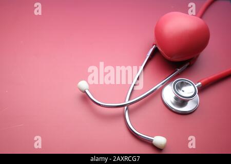 Closeup di forma del cuore e stetoscopio su sfondo rosso Foto Stock