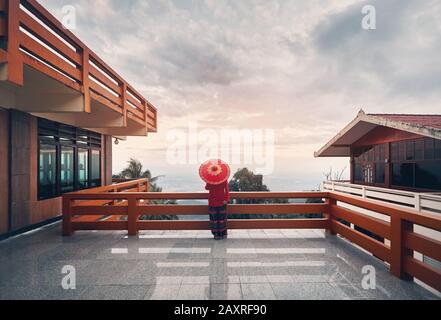 Donna con ombrello rosso tailandese guarda il panorama della città di Chiang mai dal punto di vista al tramonto cielo in Thailandia Foto Stock