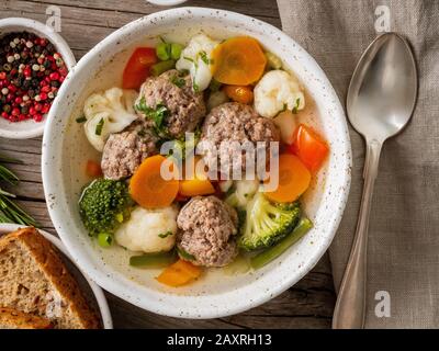 zuppa di polpette in piatto bianco su vecchio tavolo grigio rustico in legno, vista dall'alto Foto Stock