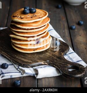 frittelle di ricotta con mirtilli su sfondo di legno scuro. Stile rustico. Cibo confortevole. Foto Stock