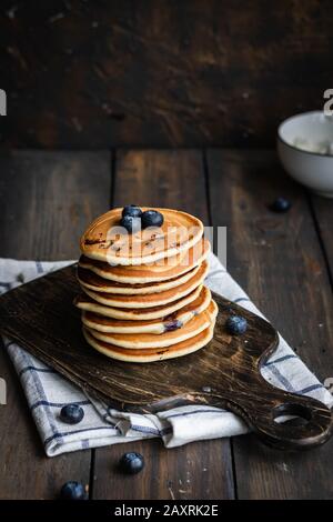 frittelle di ricotta con mirtilli su sfondo di legno scuro. Stile rustico. Cibo confortevole. Foto Stock