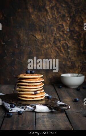 frittelle di ricotta con mirtilli su sfondo di legno scuro. Stile rustico. Cibo confortevole. Foto Stock