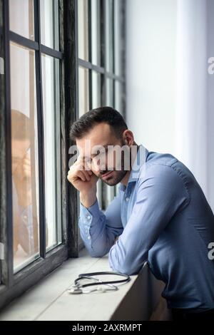 Giovane uomo con bearded in camicia blu che guarda stressato Foto Stock