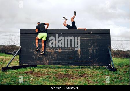 I partecipanti nel corso di ostacolo parete di arrampicata Foto Stock