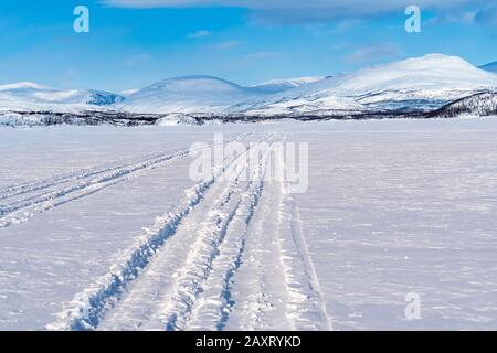 Svezia, Lapponia, Abisko, lago ghiacciato (Torneträsk), tracce di motoslitte Foto Stock